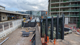 The site is sandwiched between the reinforced concrete frames of the new campus buildings and the retaining wall that supports the track bed 