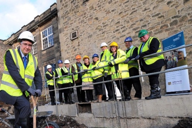 Cllr Andrew Lewer breaks ground, watched by council delegates and representatives from Wates