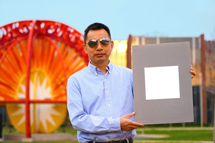 Xiulin Ruan, a Purdue University professor of mechanical engineering, holds up his lab&rsquo;s sample of the whitest paint on record. (Purdue University/Jared Pike)